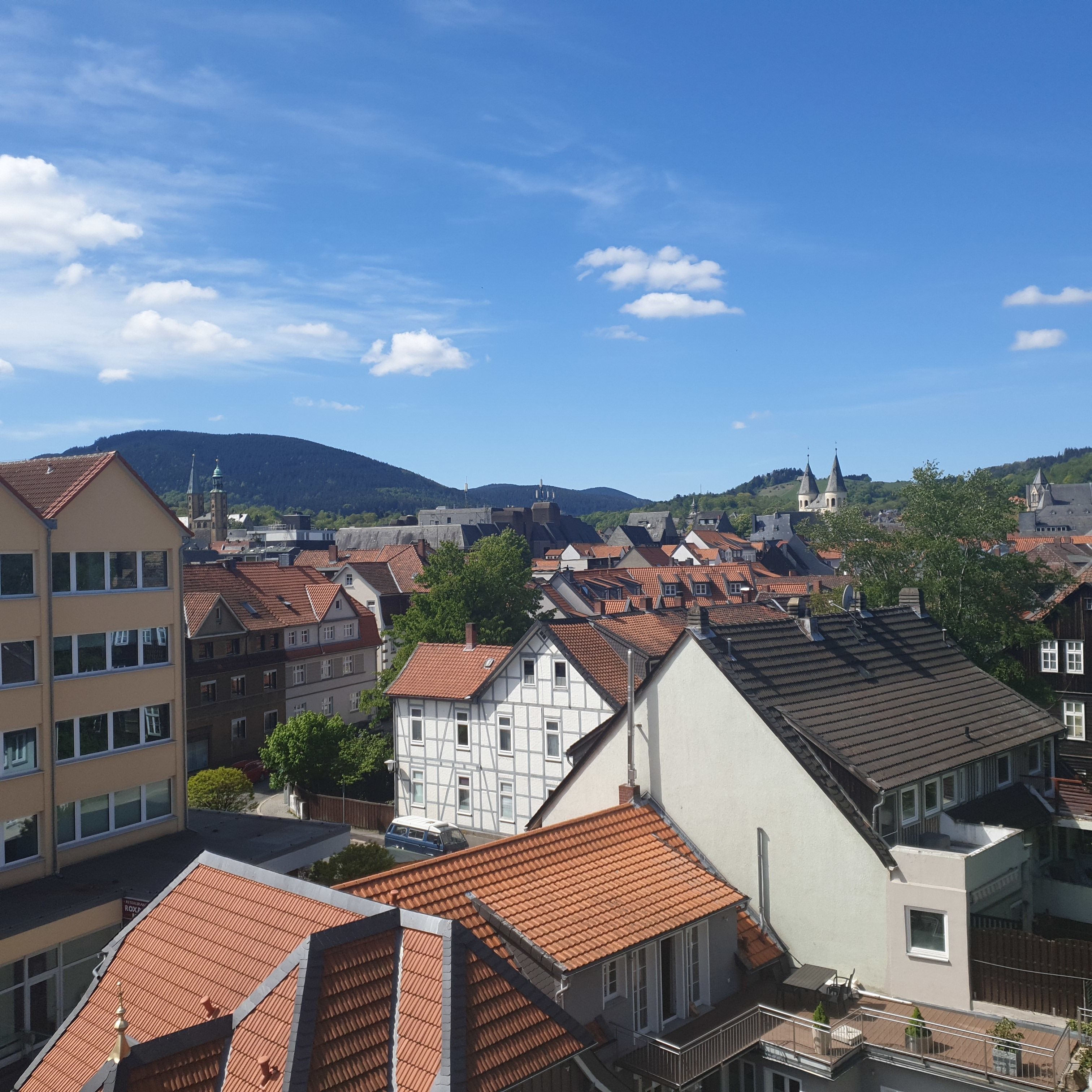 A town with traditional buildings, including a church with a tall spire, and a hill in the background.