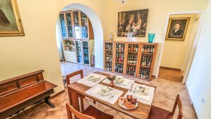 A dining area with a wooden table set for four, surrounded by chairs. A cabinet with liquor bottles is in the background. - Scognamiglio Suites (Ercolano)