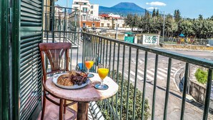 A balcony with a table, chairs, and a plate of food. - Scognamiglio Suites (Ercolano)