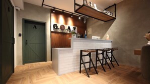 Un espace bar moderne avec un comptoir en bois, des tabourets de bar et une enseigne indiquant « GOAT BAR ».