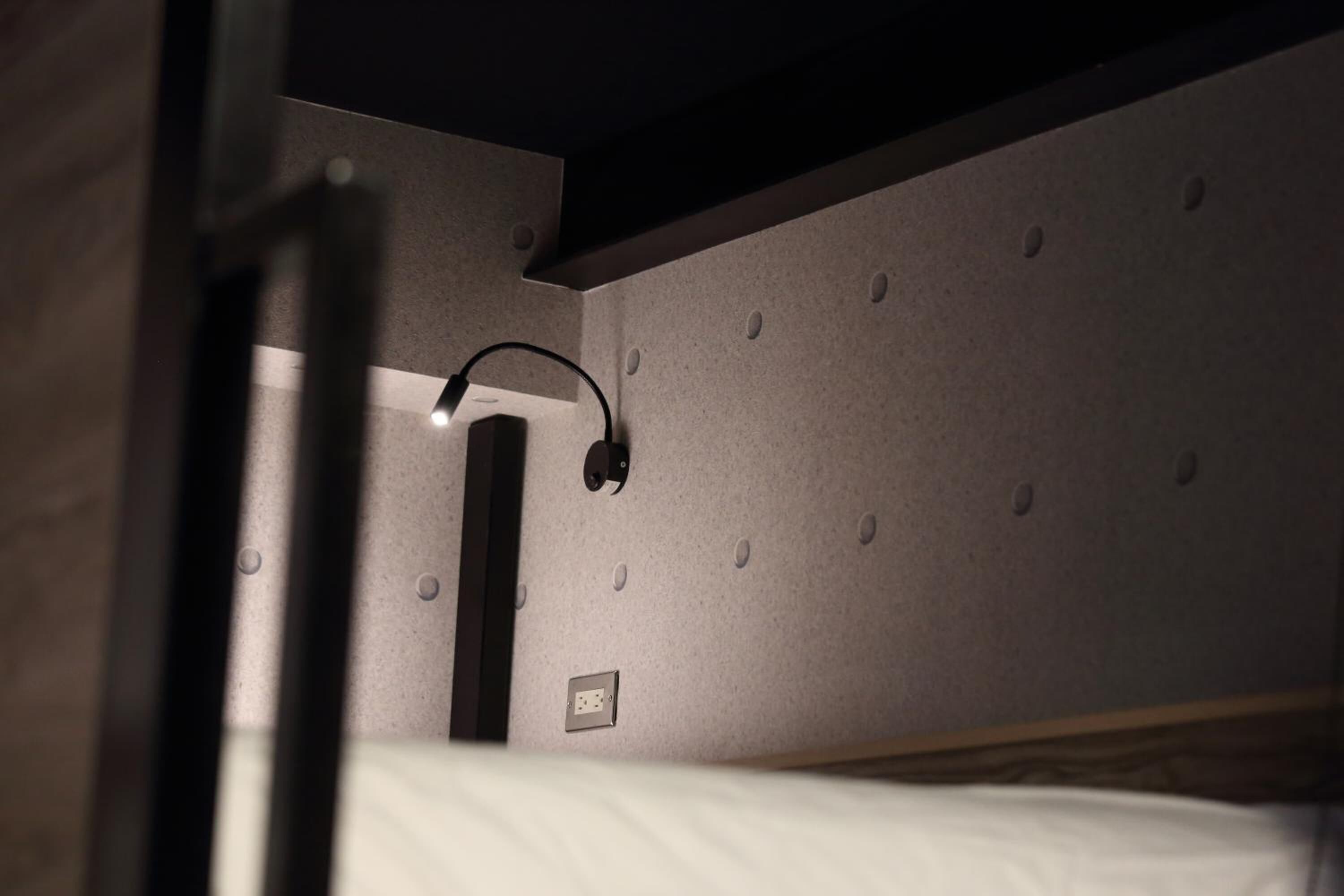 A bunk bed with a headboard and a wall-mounted light fixture.