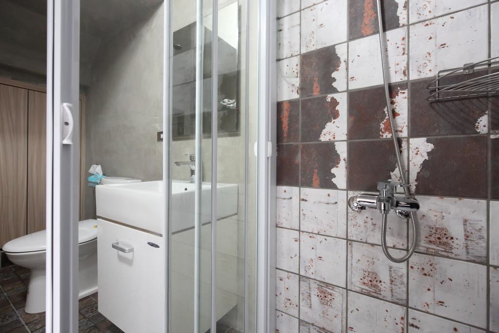 A bathroom with a glass shower enclosure, a toilet, and a sink.