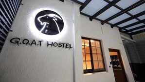 Une auberge de jeunesse avec une enseigne indiquant « GOAT HOSTEL » et un logo au-dessus.