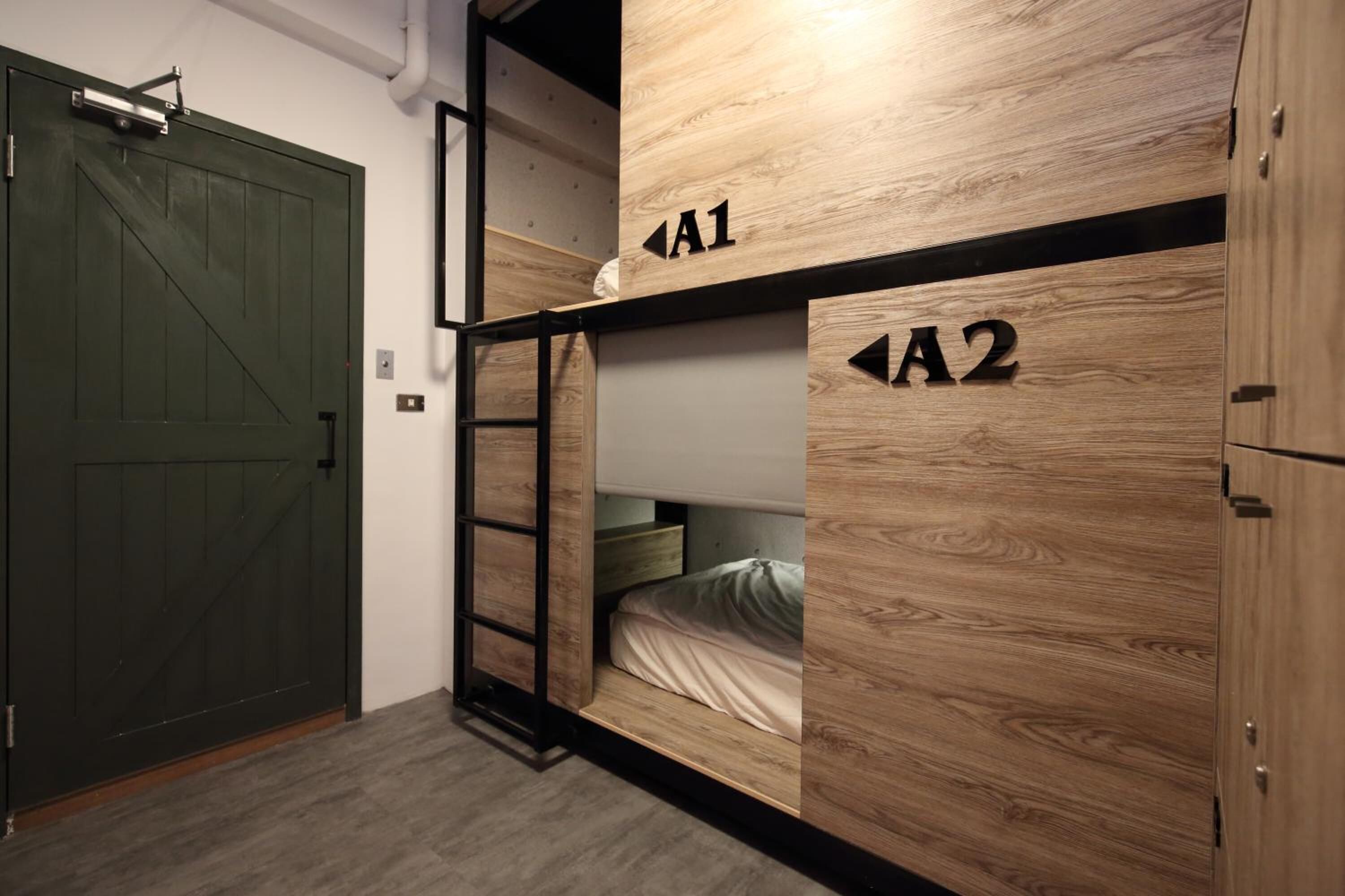 A room with bunk beds labeled A1 and A2, a ladder, and a green door.
