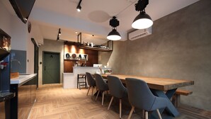 Une cuisine moderne avec un plan de travail en bois, un coin repas avec des chaises et un bar avec un comptoir et des tabourets.