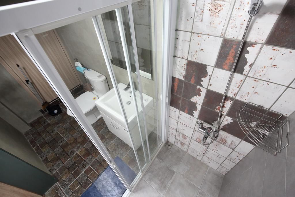 A bathroom with a glass shower enclosure, a toilet, and a sink.