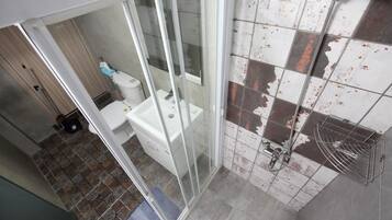 A bathroom with a glass shower enclosure, a toilet, and a sink.