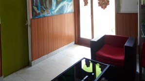 Een kamer met een grote muurschildering, een rode stoel en een glazen tafel.
