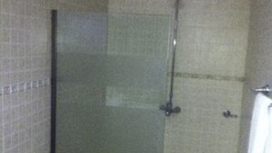 A bathroom with a toilet, a glass-enclosed shower, and a towel rack. - Margalla Lodge (Islamabad)