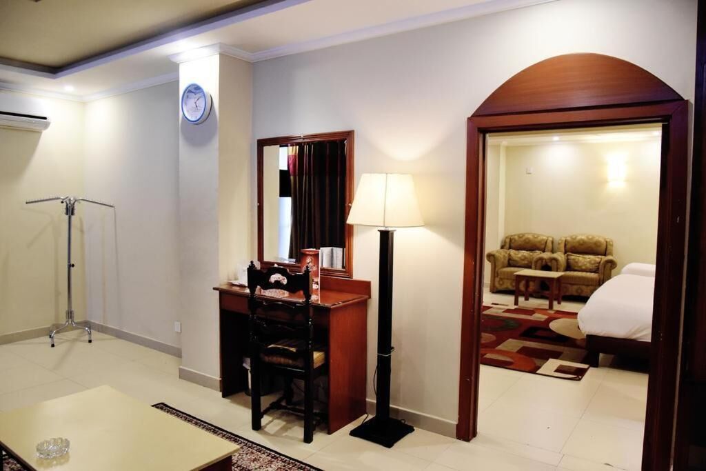 Une chambre d’hôtel équipée d’un bureau, d’une chaise, d’une lampe et d’un canapé dans l’espace salon attenant.