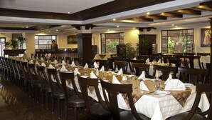 A large dining hall with long tables set for multiple guests, wooden chairs, and a modern ceiling design. - Hotel Pak Heritage (Lahore)