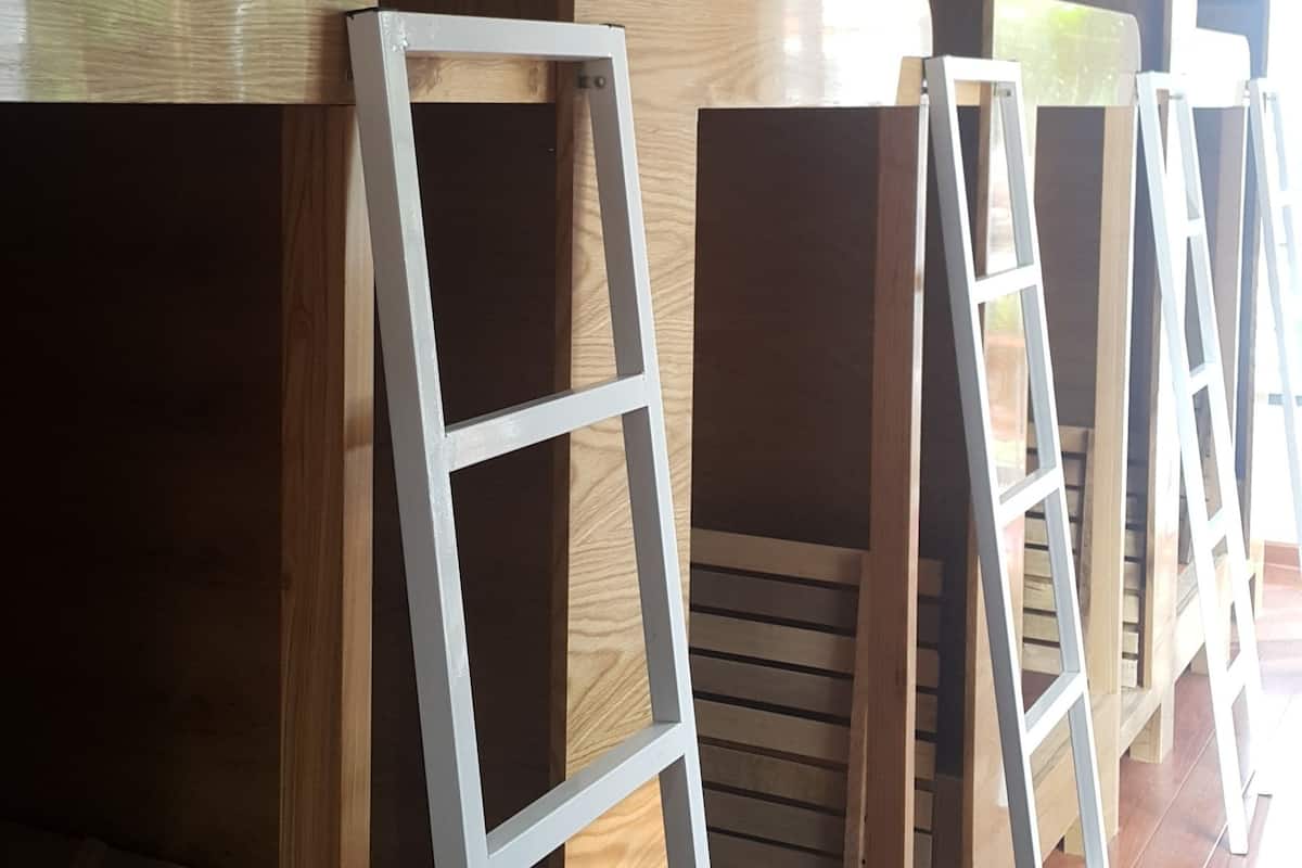 A row of bunk beds with white metal ladders, wooden panels, and a wooden floor.