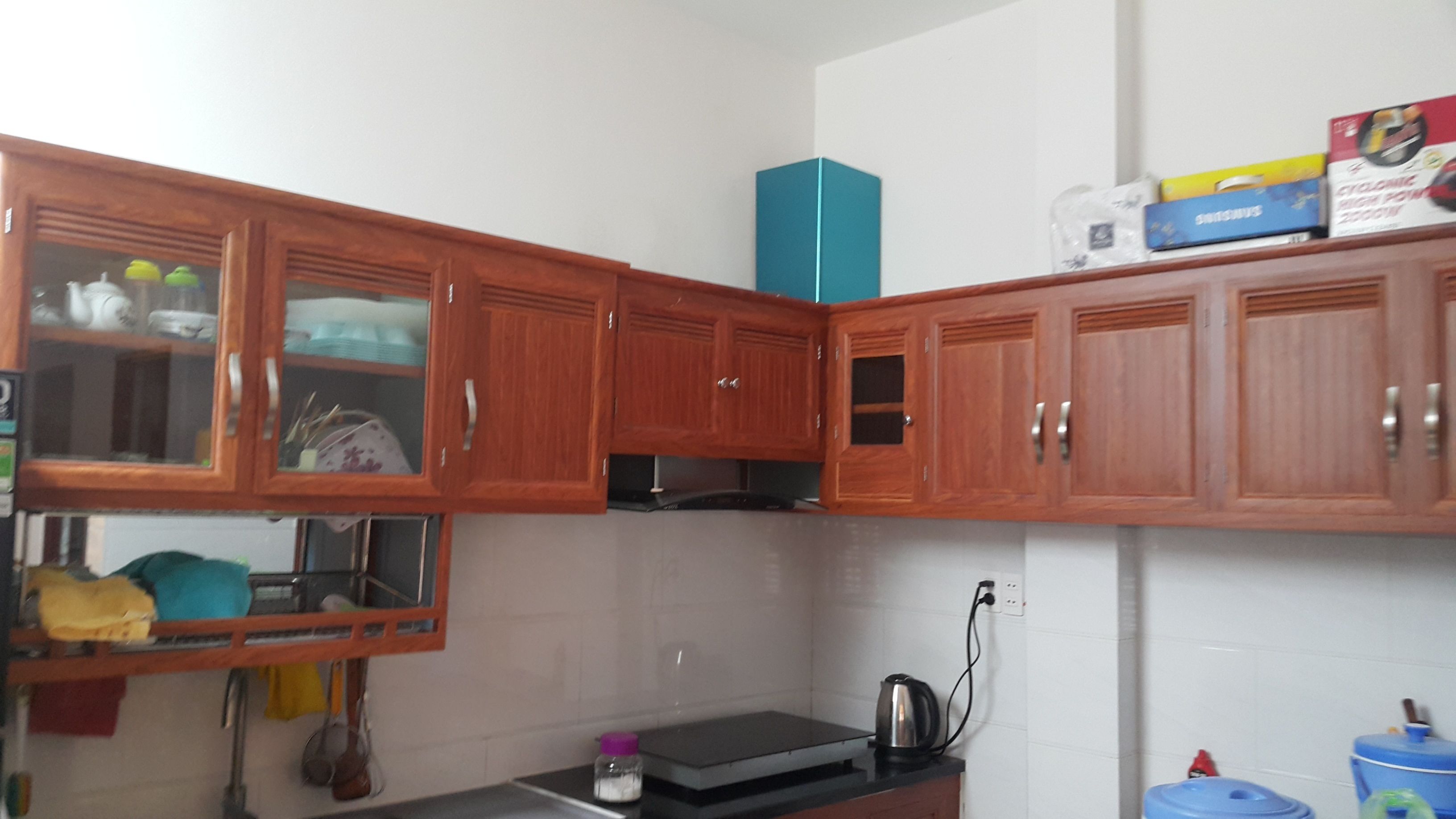 A kitchen with wooden cabinets, a black countertop, and a blue storage box on top.