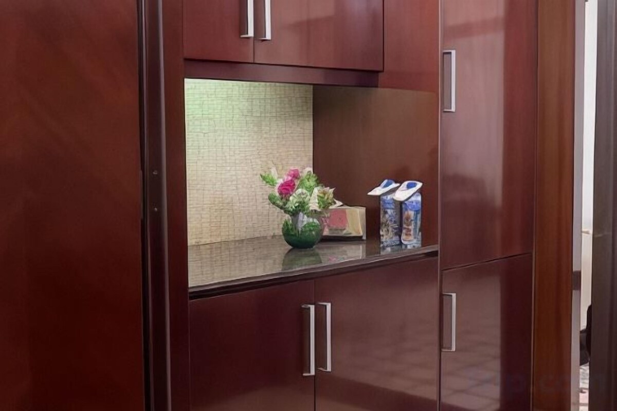Een houten kast met een spiegel, een vaas met bloemen en een zakdoekendoos.