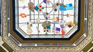 A grand octagonal skylight with intricate geometric patterns and a grid of colorful, origami-like structures suspended within.