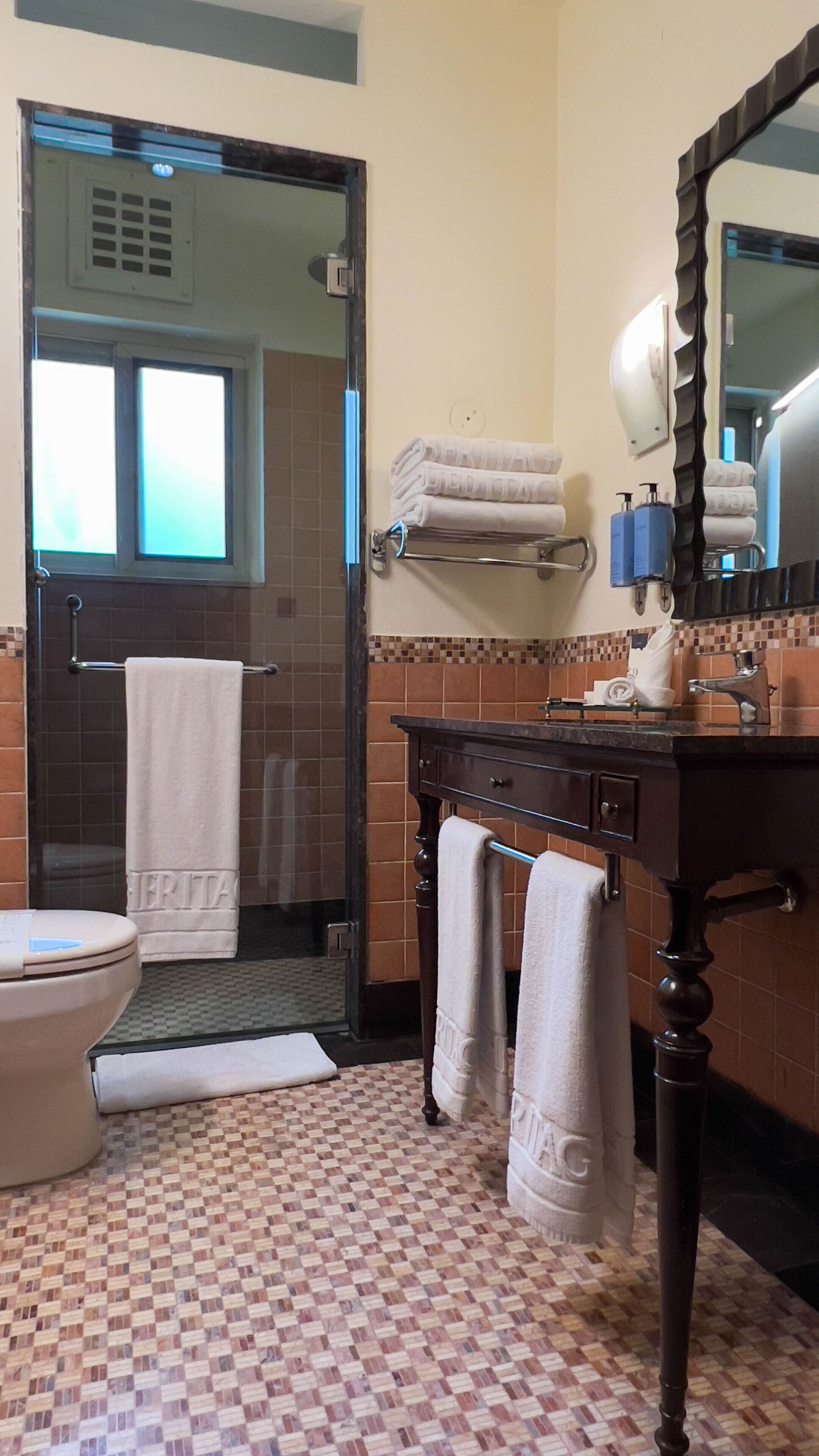 A bathroom with a checkered floor, a toilet, a sink with a mirror, and a towel rack.