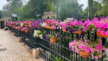 Una hilera de macetas colgantes con una variedad de flores coloridas en una valla metálica.
