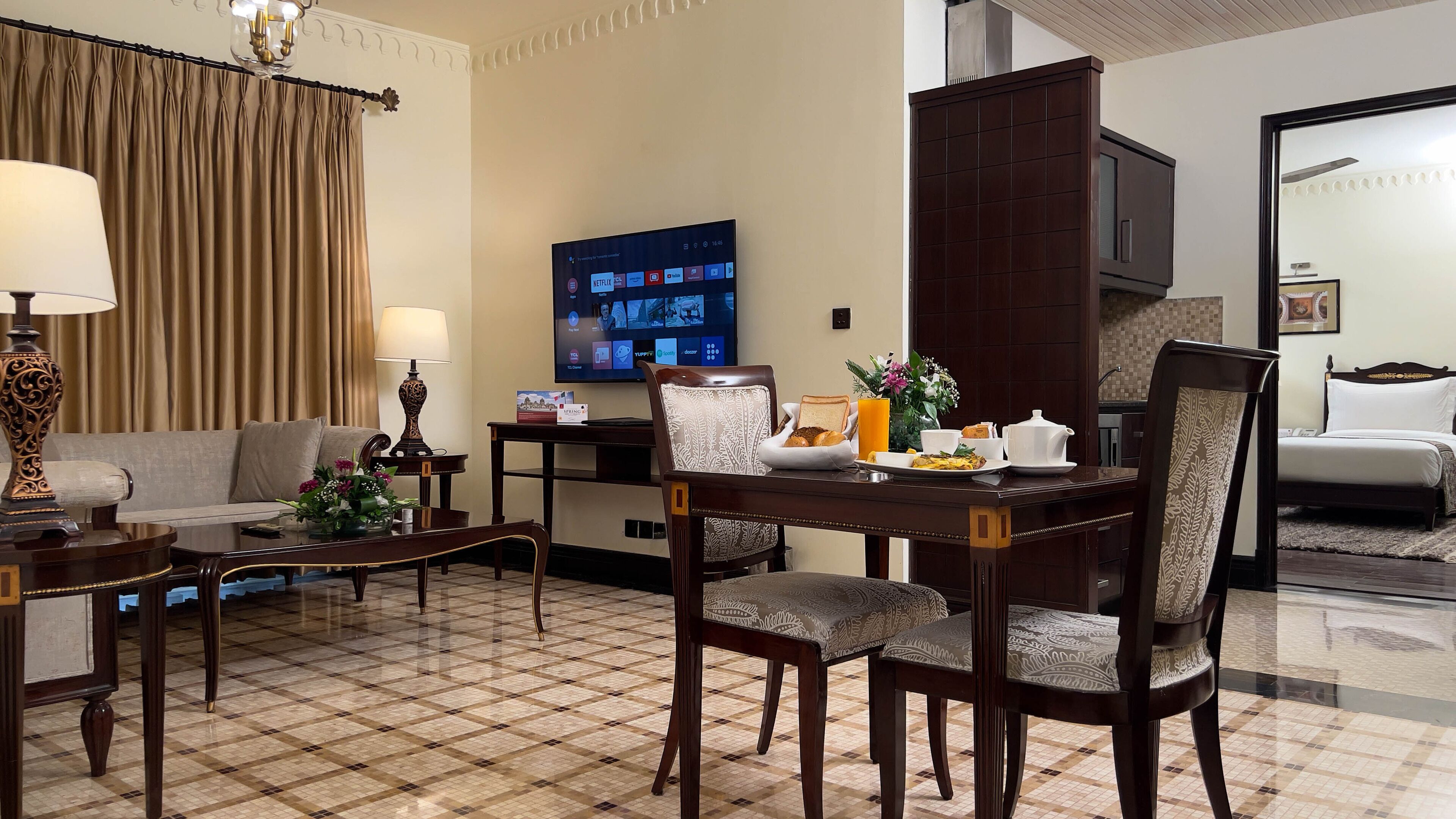 Habitación de hotel con comedor, sofá, televisor y cama.