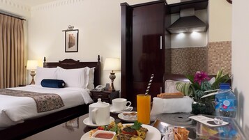Camera d'albergo con un letto, comodini, una scrivania con prodotti per la colazione, un bagno e vista sull'esterno.