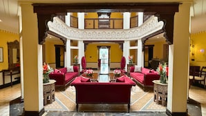 Eine Lobby mit Sitzgruppe in der Mitte, einer Treppe und Blick ins Freie.