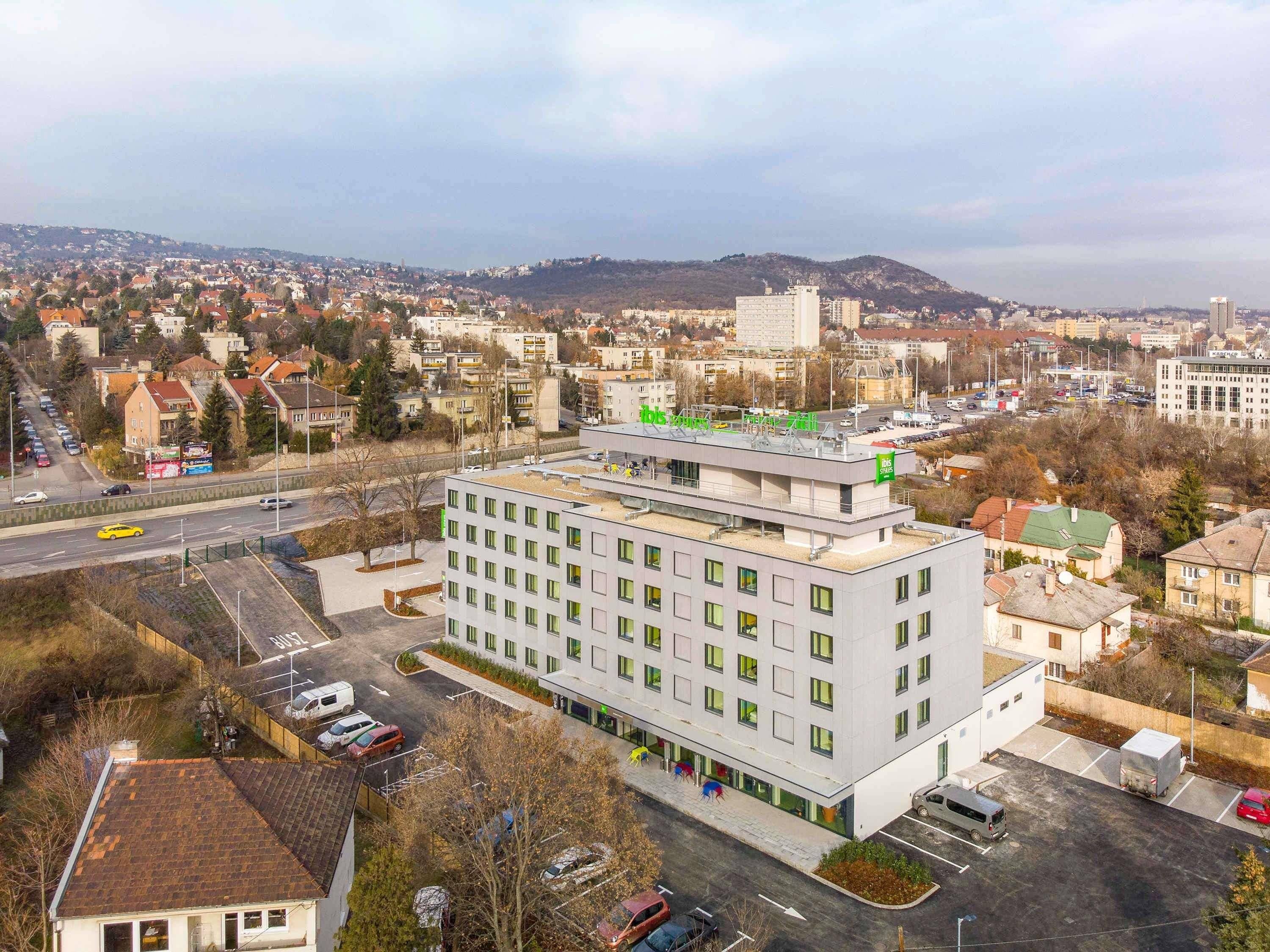 A modern hotel with a flat roof, multiple floors, and a parking area.