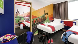 A hotel room with two beds, a desk, a chair, a dog, and a pair of shoes. - Ibis Styles Budapest Citywest (Budapest)