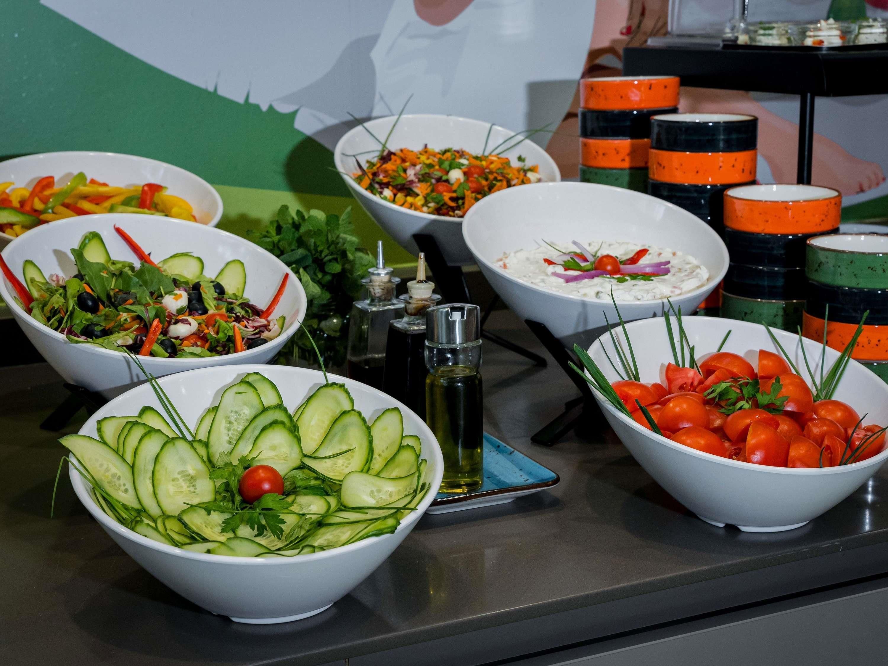 A buffet table with various bowls of salads and garnishes.