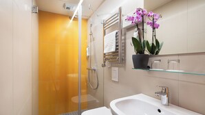 A modern bathroom with a glass shower enclosure, a white sink, and a potted orchid. - Ibis Styles Budapest Citywest (Budapest)
