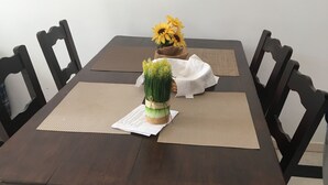 A wooden dining table with a woven placemat, surrounded by dark wooden chairs.