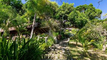 A stone staircase leading up to a thatched-roof structure surrounded by lush greenery.