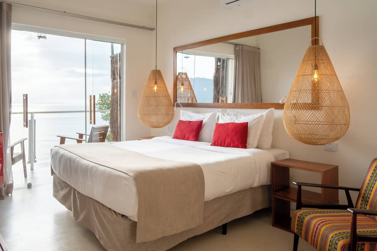 Un dormitorio con una cama grande, una mesita de noche de madera, una silla y una lámpara colgante.