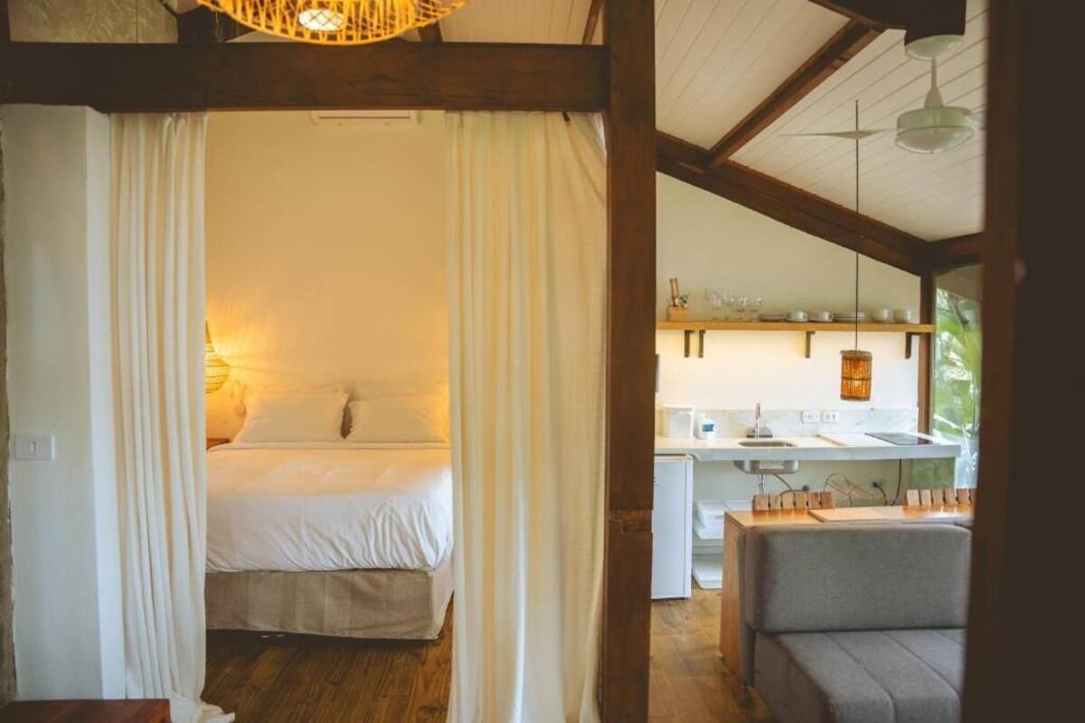 Un dormitorio con cama, una kitchenette pequeña y una zona de estar con mesa y sillas.