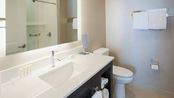 A modern bathroom with a large mirror, a sink, a toilet, and a glass shower enclosure.