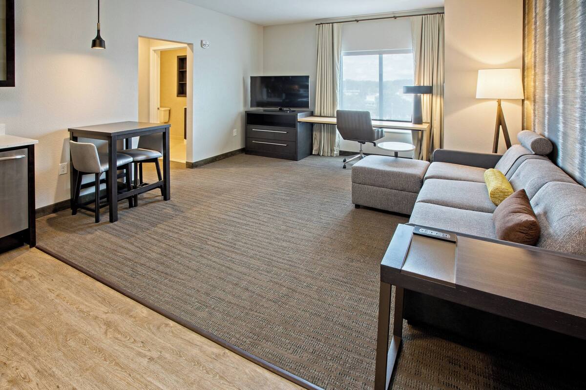 Ein Hotelzimmer mit einer Couch, einem Schreibtisch, einem Fernseher und einer Lampe.