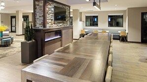 A long wooden conference table with chairs, a fireplace, and a television mounted on a wall with a mosaic backsplash. - Residence Inn by Marriott Louisville East/Oxmoor (Louisville)