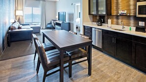 A modern hotel room with a dining area, kitchenette, and a living area with a sofa and TV. - Residence Inn by Marriott Louisville East/Oxmoor (Louisville)