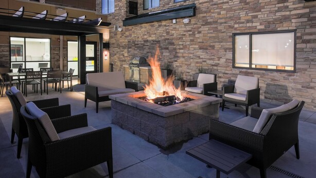 An outdoor patio with a stone fire pit, wicker furniture, and a stone wall. - Residence Inn by Marriott Louisville East/Oxmoor (Louisville)