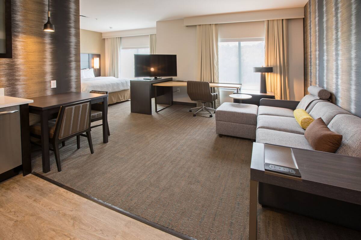 Ein Hotelzimmer mit einem Bett, einem Schreibtisch mit Fernseher, einer Sitzecke und einem Essbereich.