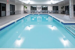 Relax by the pool surrounded by comfortable lounge chairs and lush greenery.