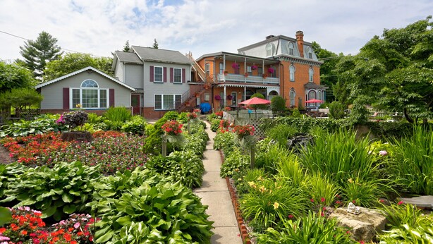 A garden pathway leading to a row of houses with a brick building in the center. -  Greystone Manor Bed & Breakfast (Bird In Hand)