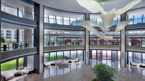 Un amplio atrium con techo alto y una escultura colgante en el centro. Se observan varios balcones con mobiliario exterior.