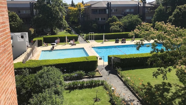 A residential area with a swimming pool surrounded by well-maintained gardens and hedges. - Apartamento en Country Pilar Frutales (Pilar)