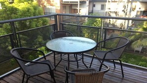 A balcony with a round glass table and four wicker chairs. - Apartamento en Country Pilar Frutales (Pilar)