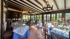 A room with wooden beams, large windows, and a chandelier. - Posada Río Cubas (Ribamontan al Monte)