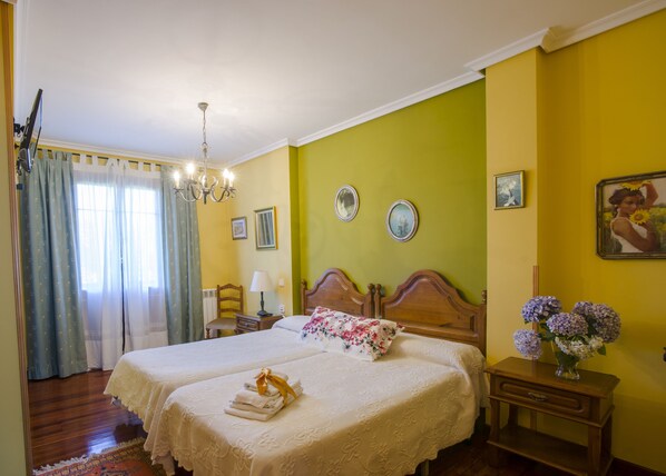 A double bed with a floral pillow and a bedside table with a vase of flowers.