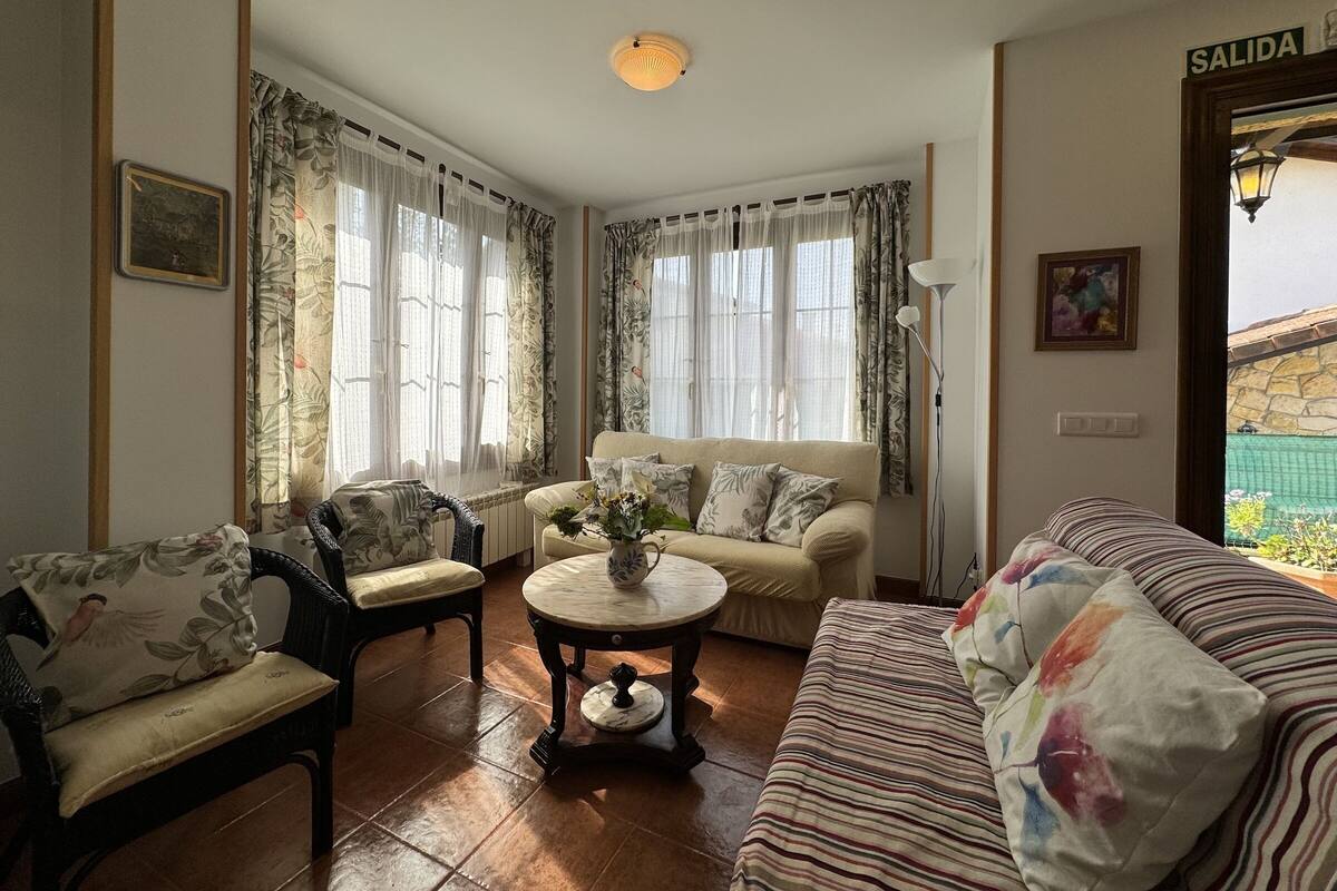A cozy living room with a sofa, armchair, and a small table with a vase.