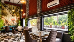 A restaurant with a checkered floor, quilted chairs, a mural of flowers, and a view of greenery outside. - Oriental Palace Resorts (Udaipur)