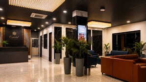 A hotel lobby with a reception desk, seating area, and a large screen.