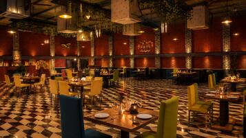 Ein Restaurant mit Schachbrettboden, Backsteinwänden, hängenden Pflanzen und mehreren Tischen mit Stühlen.