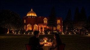 A couple dining outdoors at night with a large building in the background.